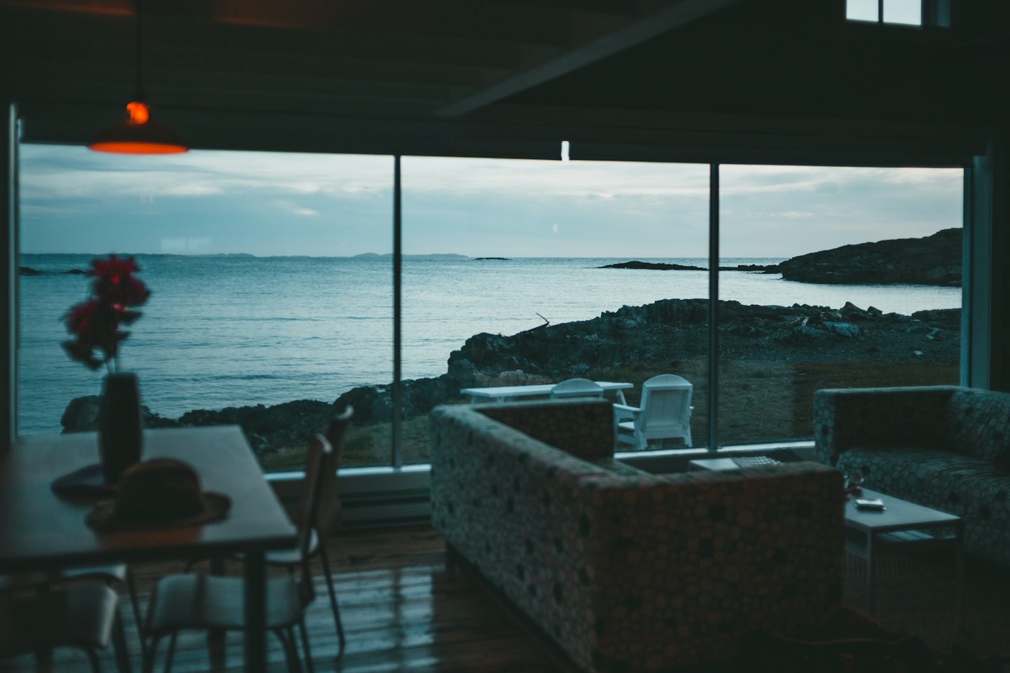 Cozy living room overlooking a rocky coastline and calm ocean.