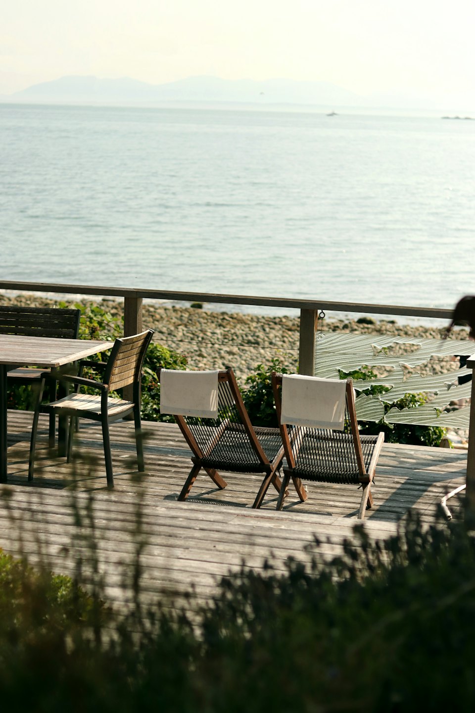 Outdoor dining set on a deck overlooking the ocean.