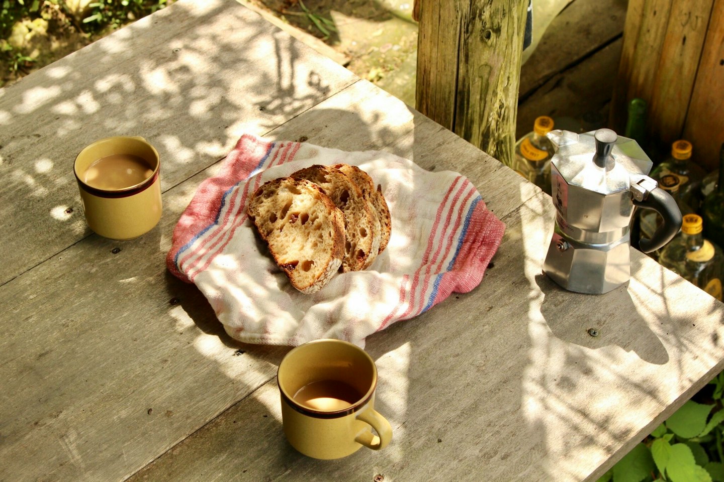 Coffee mugs and bread slices sit on a wooden table.